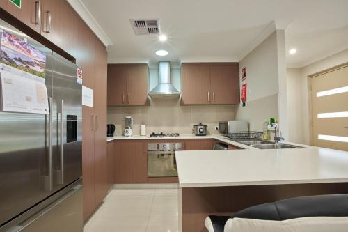 a kitchen with wooden cabinets and a stainless steel refrigerator at Gorgeous Family House near Shops in Perth