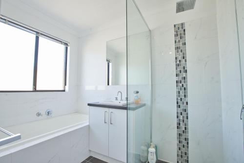 a white bathroom with a shower and a sink at Gorgeous Family House near Shops in Perth