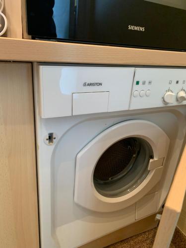 Un four micro-ondes est installé au-dessus d'un lave-linge. dans l'établissement Arcadia Studio face Mer avec parking, à Le Touquet-Paris-Plage