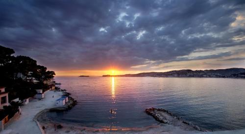 a sunset over a body of water with the sun setting at Hostellerie La Farandole in Sanary-sur-Mer