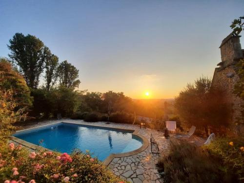 une piscine dans une cour avec un coucher de soleil en arrière-plan dans l'établissement La grande marque - Veprado, à Marnac