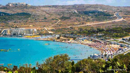 a beach with a bunch of people in the water at Seafront Apartment in St. Paul's Bay in St Paul's Bay