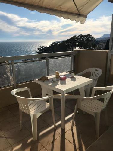 une table blanche et des chaises sur un balcon avec l'océan dans l'établissement Seahouse Menton Garavan, à Menton