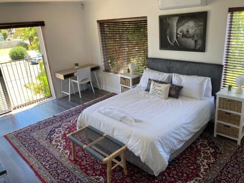 a bedroom with a large white bed and a table at The Elephant House in Cape Town