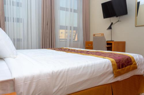 a bedroom with a large white bed and a television at Tropical Plaza Apartments in Kigali
