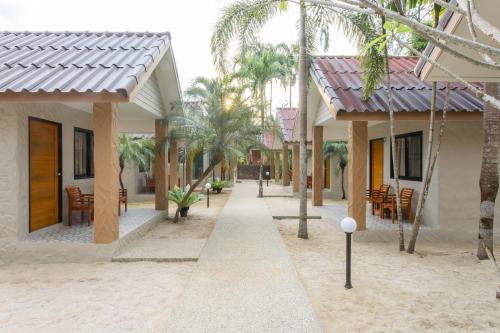 a street with houses and chairs and palm trees at Lightplus Khao Lak in Khao Lak