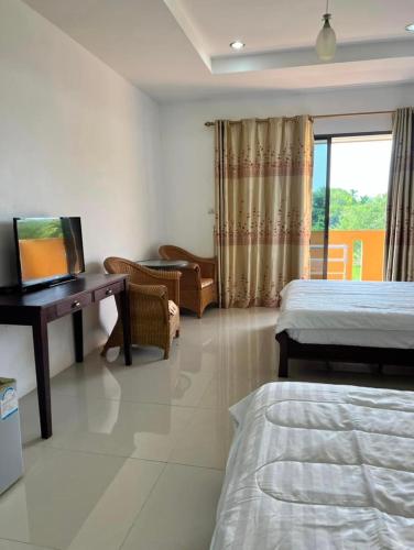 1 dormitorio con 2 camas, escritorio y ventana en Relaxation guesthouse en Thalang