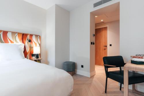 a bedroom with a bed and a desk and a chair at Padam Hôtel in Paris