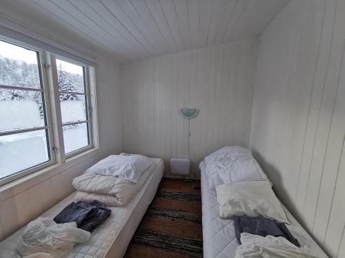 two beds in a small room with two windows at Tangen - cabin with 4 bedrooms - great nature in Norheimsund