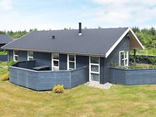 a blue house with a metal roof on a yard at 6 person holiday home in L kken in Løkken