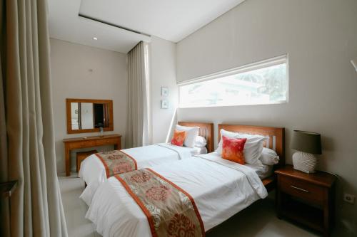 two beds in a hotel room with a window at The Lavana River Villas Lombok in Senggigi