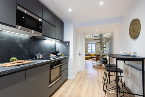 une cuisine avec des armoires noires et un comptoir dans l'établissement Sweett - Atelier Bastille, à Paris