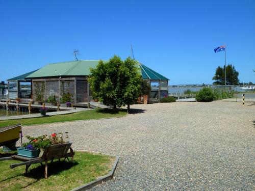 a park with a building and a bench with flowers at Boat Haven Studios in Goolwa