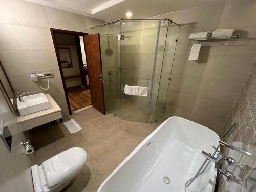 a bathroom with a shower and a tub and a toilet at Pinaka Hotels & Resorts in Haridwār