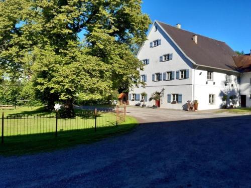 een groot wit huis met een hek ervoor bij Rösslerhof Ferienwohnung Lindele 