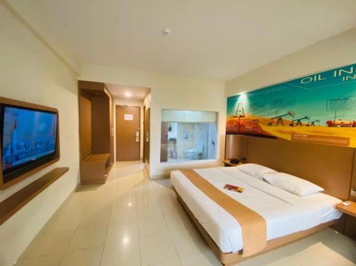 a bedroom with a large bed and a flat screen tv at Comforta Dumai in Dumai