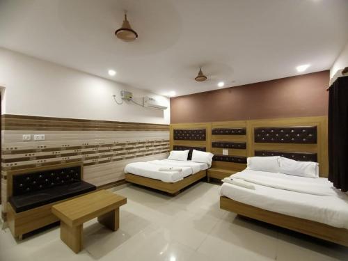 a room with two beds and a bench in it at Chhabra Guest House, Kanpur in Kānpur