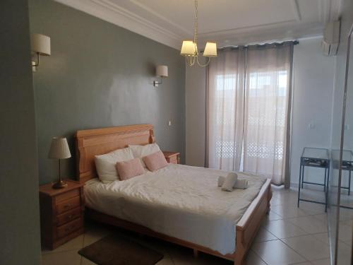 a bedroom with a bed with white sheets and pink pillows at Grand appartement calme et lumineux + Parking GRATUIT in Casablanca