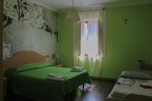 una camera verde con un letto e una finestra di Casa Margherita a Sellia Marina