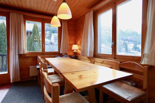 a wooden table and chairs in a room with windows at Chalet Arabesque - Switzerland in Grächen