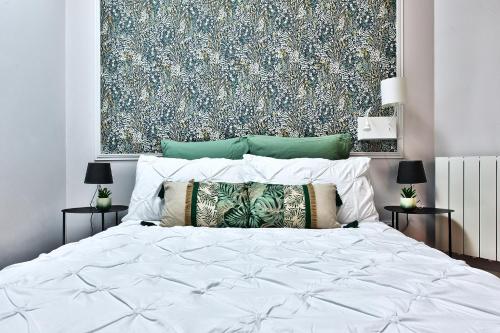 1 dormitorio con 1 cama blanca y una gran pintura en la pared en Appartement L’Élégant - Idéalement Situé, en Écully