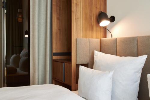 Habitación de hotel con cama con almohadas blancas en Cocoon Sendlinger Tor, en Múnich