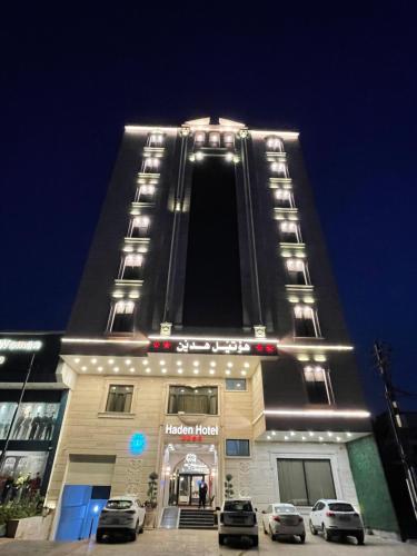 um edifício alto com carros estacionados em frente em Haden Hotel em Erbil