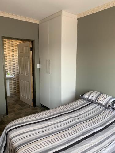 a bedroom with a bed and a closet and a door at Orlando Manor in Soweto
