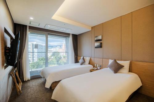 a hotel room with two beds and a window at Hotel bridge Seogwipo in Seogwipo