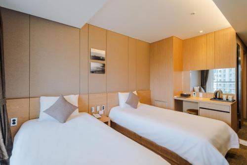 a hotel room with two beds and a kitchen at Hotel bridge Seogwipo in Seogwipo