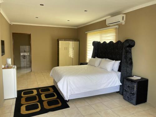 a bedroom with a large bed with a black headboard at 3 Schnehage Guesthouse in Welkom