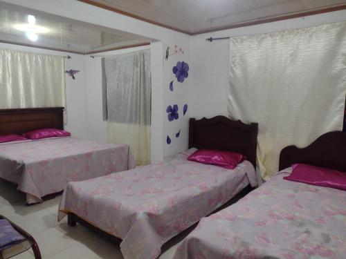 two beds in a bedroom with pink sheets at hostal Sueño Paraiso- Observatorio astronómico in Popayan