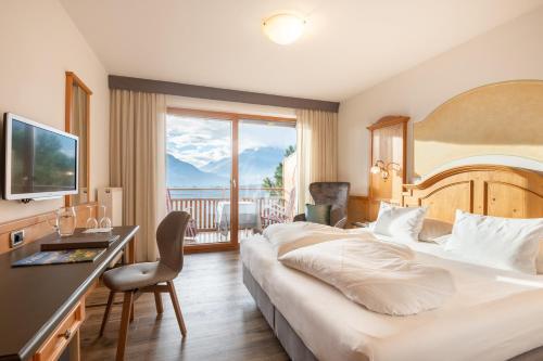 a hotel room with a bed and a desk and a balcony at Hotel Garni Nachtigall in Schenna