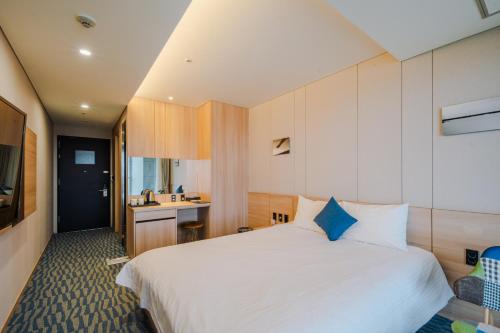 a bedroom with a large white bed and a sink at Hotel bridge Seogwipo in Seogwipo
