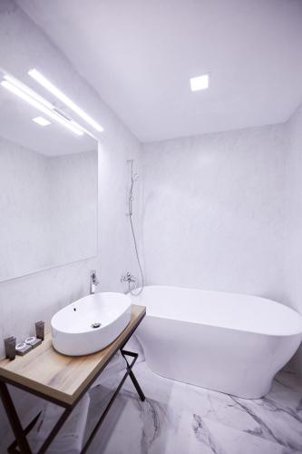 a white bathroom with a large tub and a sink at Hotel Belvedere in Braşov