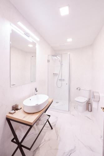 a white bathroom with a sink and a shower at Hotel Belvedere in Braşov