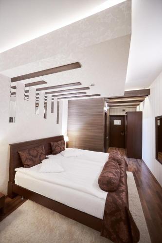a bedroom with a large white bed and a large chandelier at Hotel Belvedere in Braşov