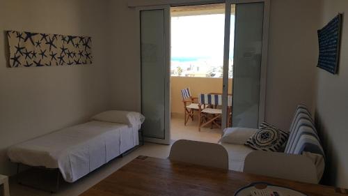 ein Schlafzimmer mit einem Bett und ein Wohnzimmer mit einem Fenster in der Unterkunft Casa CostaSud in Marina di Ragusa