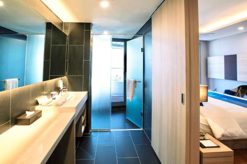 a bathroom with a sink and a bed at Hotel bridge Seogwipo in Seogwipo