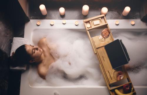 a woman laying in a bath tub with a bath tub at Bohemian Suites Athens in Athens