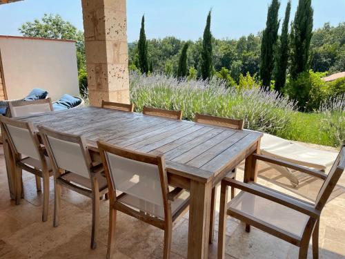 a wooden table and chairs on a patio at Domaine de la Durantie - Villas avec Spa de nage in Castelnau-de-Montmiral