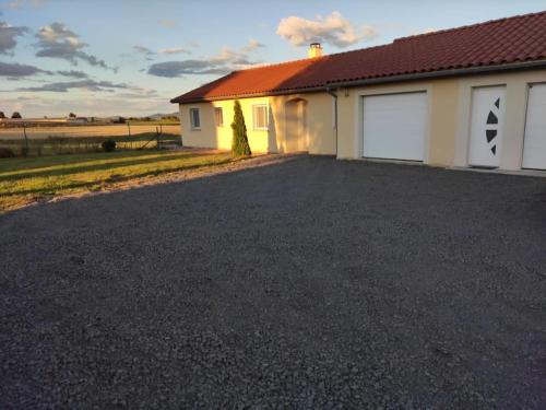 a house with two garage doors and a driveway at Maison entière de plein pied avec vue panoramique. in Venteuges