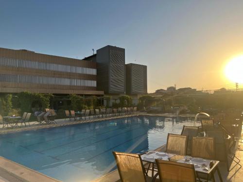 a swimming pool with tables and chairs in a building at Abu Sanaa Hotel in As Sulaymānīyah