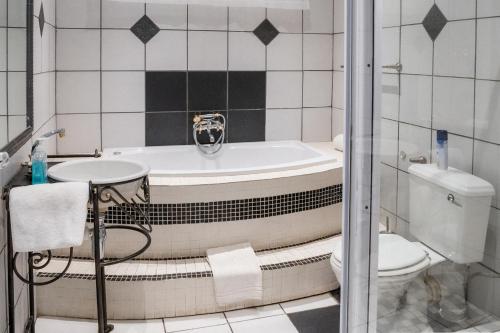 a bathroom with a tub and a toilet at Park Living Guesthouse in Bloemfontein