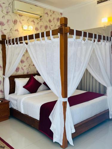 a bedroom with a canopy bed with white curtains at The Fog Munnar (Resort & Spa) in Munnar