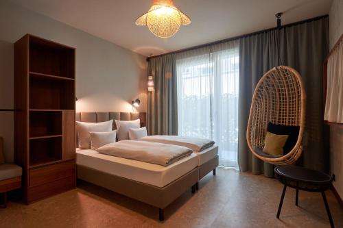 a bedroom with a bed and a hanging chair at Cocoon Sendlinger Tor in Munich