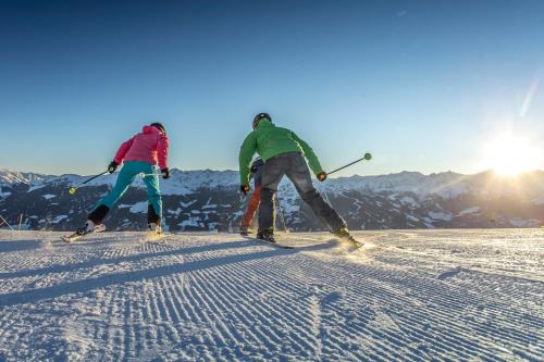 two people are skiing down a snow covered slope at Landhaus Kostenzer mit Sauna in Fügen