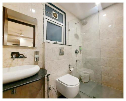 La salle de bains est pourvue de toilettes, d'un lavabo et d'un miroir. dans l'établissement Qotel Hotel Church House Rohini Sector 15- Couple Freindly, à New Delhi