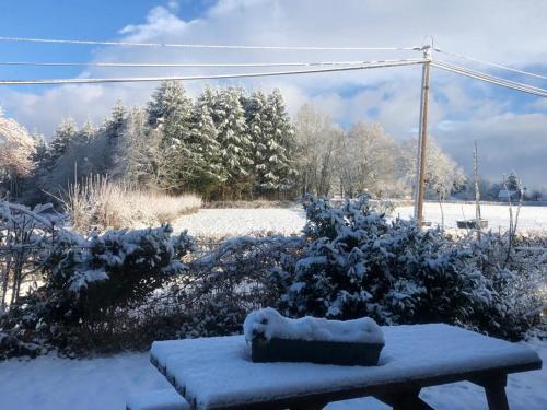 a bench covered in snow in a yard at Maison de Campagne in Sarroux