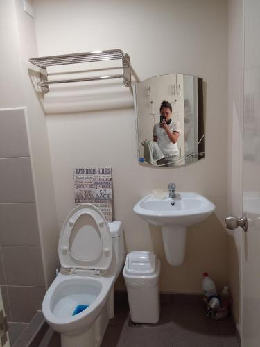 un hombre tomando una foto de un baño con aseo y lavabo en LPP CONDO UNIT AT AVIDA ASPIRA CONDOMINIUM, en Cagayan de Oro